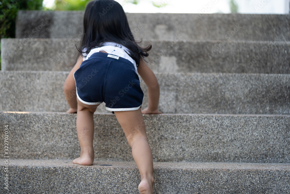 Toddler asian girl climbing and walking down the stairs at home.Concept of happy childhood and Child development.