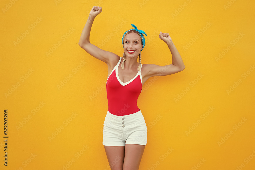 Happines and summer vacation. Young excited woman with rised hands against yellow wall. Happines and summer vacation. Young excited woman with rised hands against yellow wall.