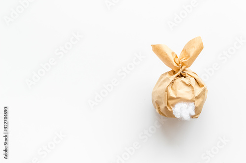 Easter gift in shape of bunny with tail on white background top-down copy space