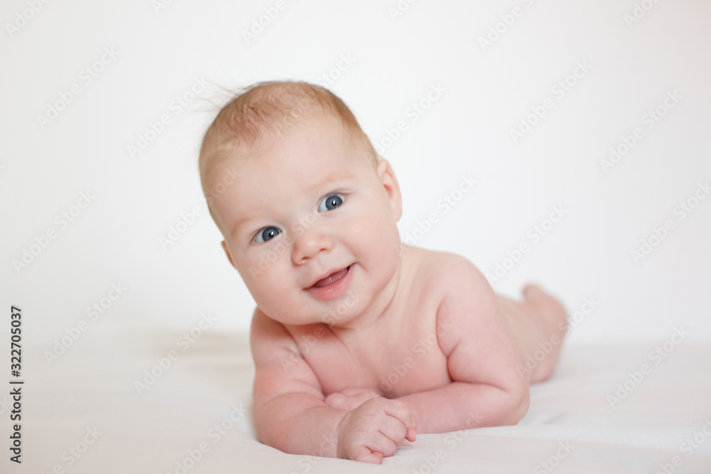 small child, baby lies on his stomach and smiles. On a white background. Newborn baby. three months old baby. A baby of European appearance. small child, baby lies on his stomach and smiles. On a white background. Newborn baby. three months old baby. A baby of European appearance.