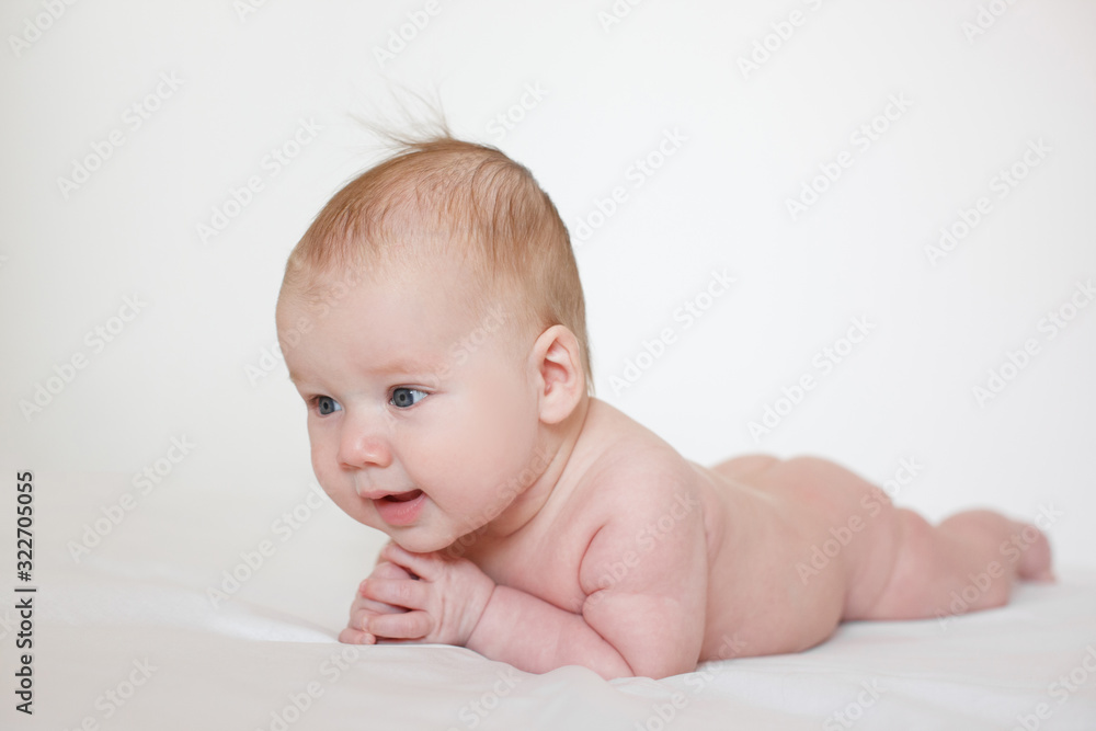 small child, baby lies on his stomach and smiles. On a white background. Newborn baby. three months old baby. A baby of European appearance. small child, baby lies on his stomach and smiles. On a white background. Newborn baby. three months old baby. A baby of European appearance.
