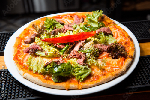 Pizza with meat and salad.