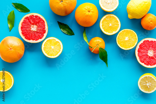 Citrus fruits frame - halfs of lemons  grapefruits  leaves - on blue background top-down copy space