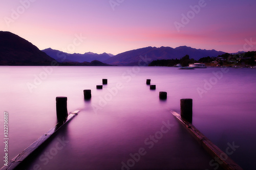 Fototapeta Naklejka Na Ścianę i Meble -  Picturesque sunset landscape wharf on lake in mountains. Lake Wanaka, New Zealand.