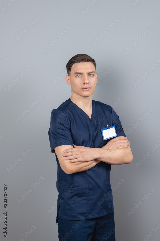 Man in a dark-blue uniform standing with his arms crossed Man in a dark-blue uniform standing with his arms crossed