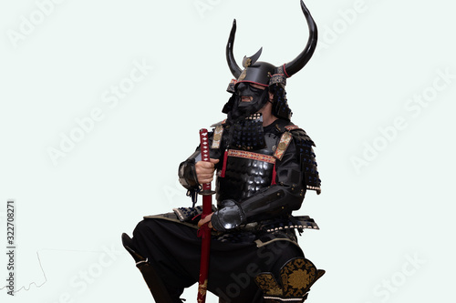 samursai warrior with black armor. He is sitting and posing