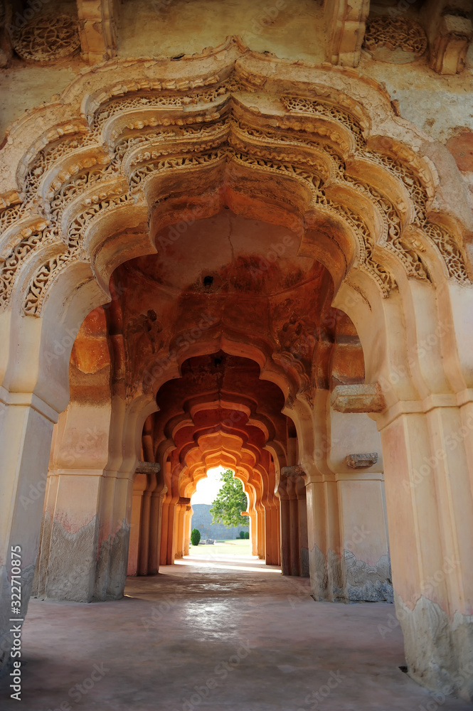 Intricate carvings on the arched hallway Lotus Mahal Temple in Hampi, Karnataka, India. Beautiful carved stone arch. Popular tourist place.