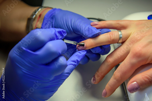 Professional manicure  nail polish in the beauty salon. Process of applying the fixing layer to the nail with a brush.