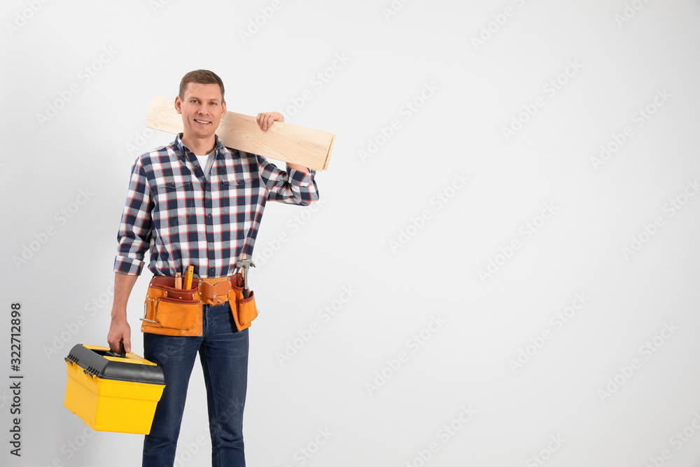 Handsome carpenter with wooden planks on light background. Space for text Handsome carpenter with wooden planks on light background. Space for text