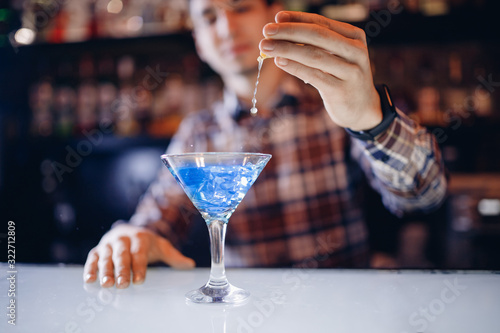 Large cocktail in martini glass with droplets of spray is prepared by barman