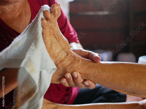 Canvas Print Hands of a woman holding an older person's feet, while gently wiping / cleaning