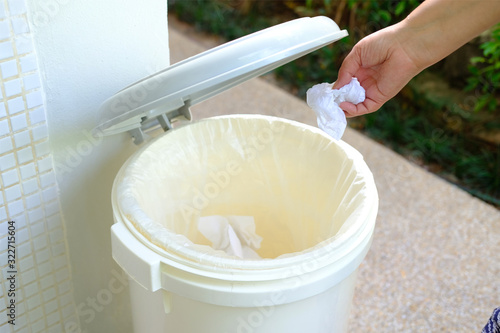 The hand holding the tissue paper for tipping into the trash