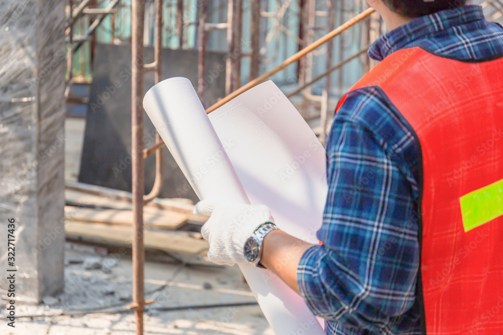 Engineer man checking and planning project at construction site, Man holding blueprint selective focus on paper Engineer man checking and planning project at construction site, Man holding blueprint selective focus on paper