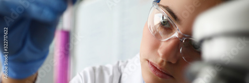 Foto Close-up of female face investigating vial with bright pink liquid