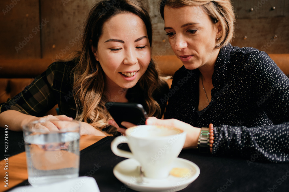 Two female friends in a cafe having coffee, smiling and chatting Two female friends in a cafe having coffee, smiling and chatting