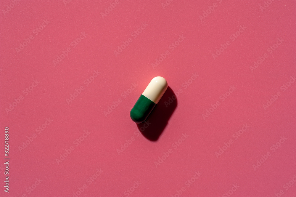 Close-up of one pill lies on a pink surface Close-up of one pill lies on a pink surface