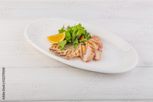 chicken breast with green salad on a white wooden background