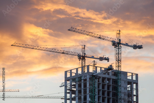 construction site with cranes against the background of bright evening clouds