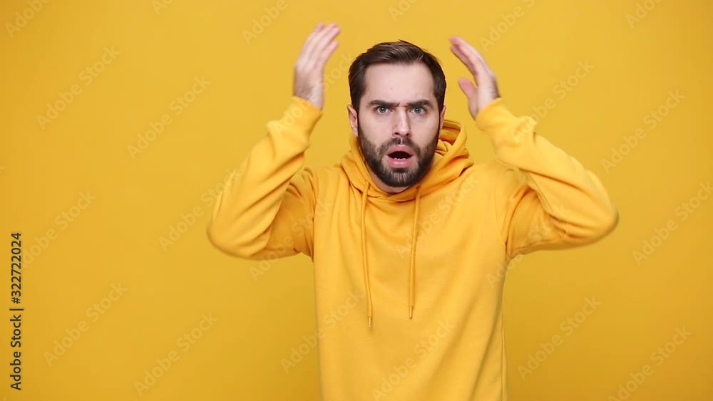 Shocked sad surprised nervous displeased irritated bearded young guy 20s in streetwear hoodie isolated on yellow background studio. People sincere emotions, lifestyle concept. Say what spreading hands Shocked sad surprised nervous displeased irritated bearded young guy 20s in streetwear hoodie isolated on yellow background studio. People sincere emotions, lifestyle concept. Say what spreading hands