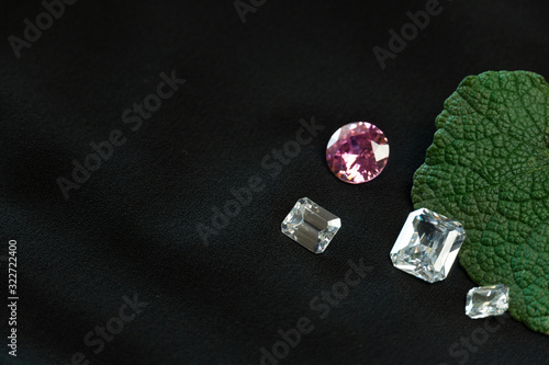luxury pink and white precious gemstone with green rough leave with black fabric fashion industry background