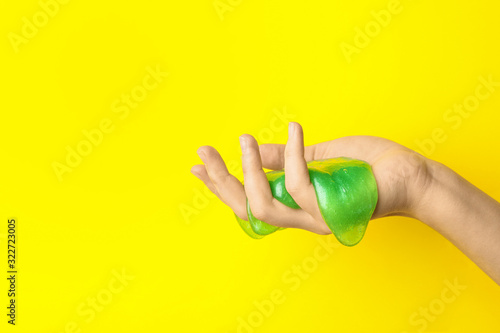 Woman playing with green slime on yellow background, closeup. Antistress toy