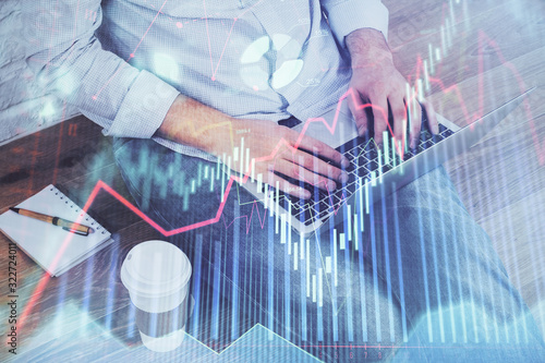 Forex graph with businessman working on computer in office on background. Concept of analysis. Double exposure.