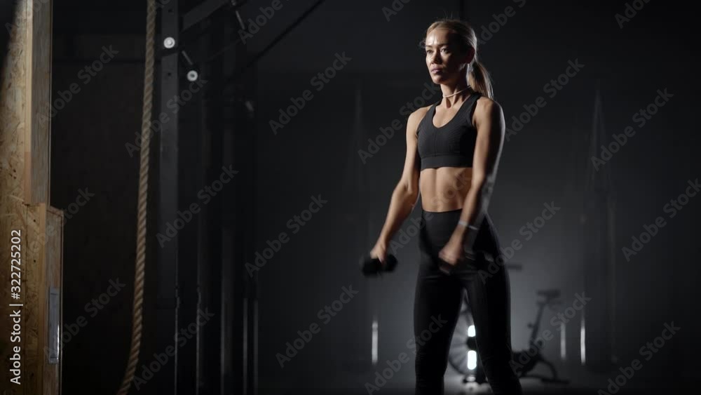 slim woman is performing physical exercise with dumbbells in gym, crouching with weight, keeping fit slim woman is performing physical exercise with dumbbells in gym, crouching with weight, keeping fit