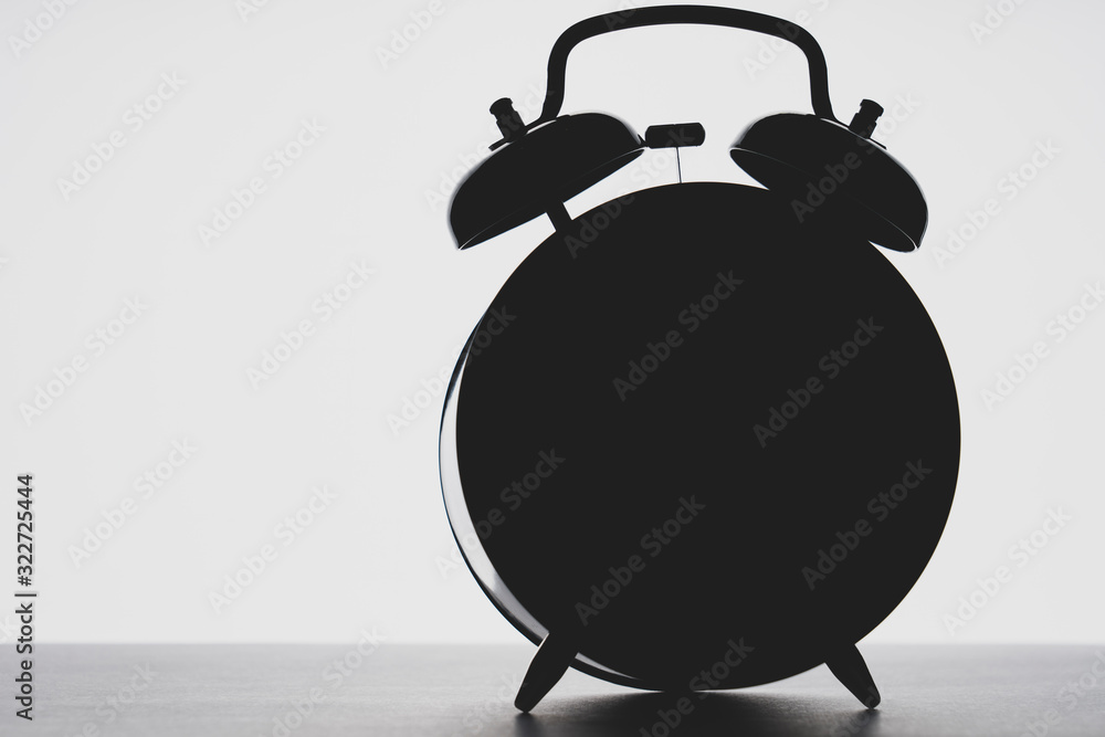 outline of the alarm clock in the dark, toning, selective focus, space for text on the left - obrazy, fototapety, plakaty 