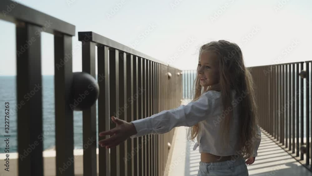 Child girl walking outside, touching metal fence and smiling wide Child girl walking outside, touching metal fence and smiling wide