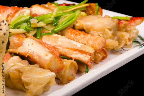 crab legs in a batter with green onions on a black background