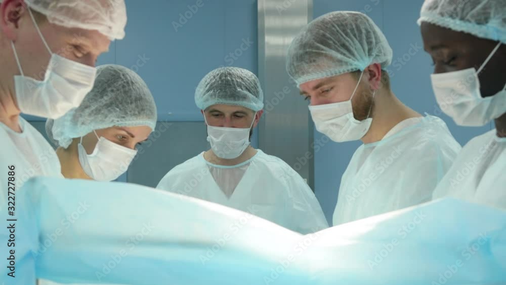 The senior surgeon in the operating room, where the patient is waiting for him, and he begins the operation. Real Modern Hospital with Authentic Equipment. The senior surgeon in the operating room, where the patient is waiting for him, and he begins the operation. Real Modern Hospital with Authentic Equipment.