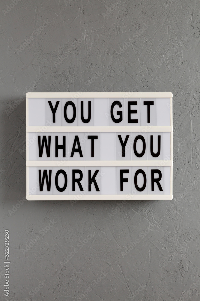 'You get what you work for' words on a modern board on a gray background, top view. Overhead, from above, flat lay. 'You get what you work for' words on a modern board on a gray background, top view. Overhead, from above, flat lay.