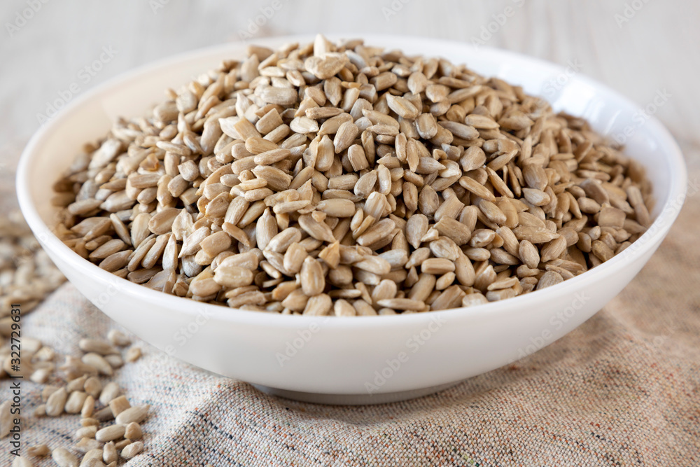 Raw Sunflower Seed Kernels in a white bowl on a white wooden background, side view. Close-up. Raw Sunflower Seed Kernels in a white bowl on a white wooden background, side view. Close-up.