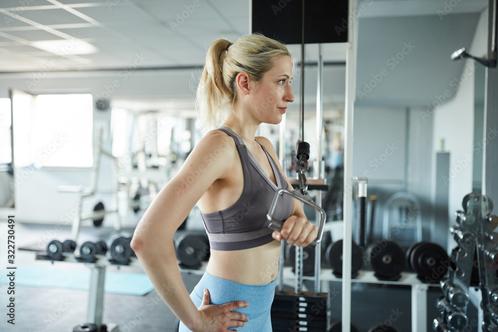 Fototapeta premium Woman doing strength training for the triceps on the cable
