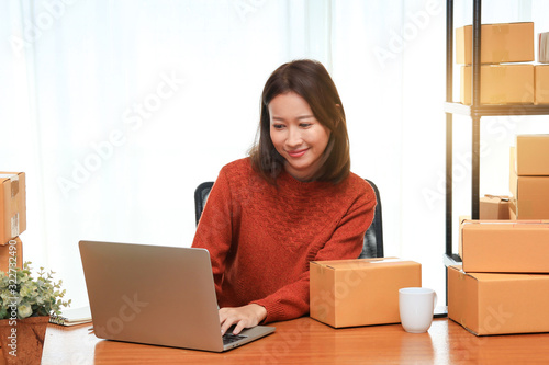Shipping shopping online, young attractive entrepreneur business woman working at home office with many packaging cardboard box © Rakchanok