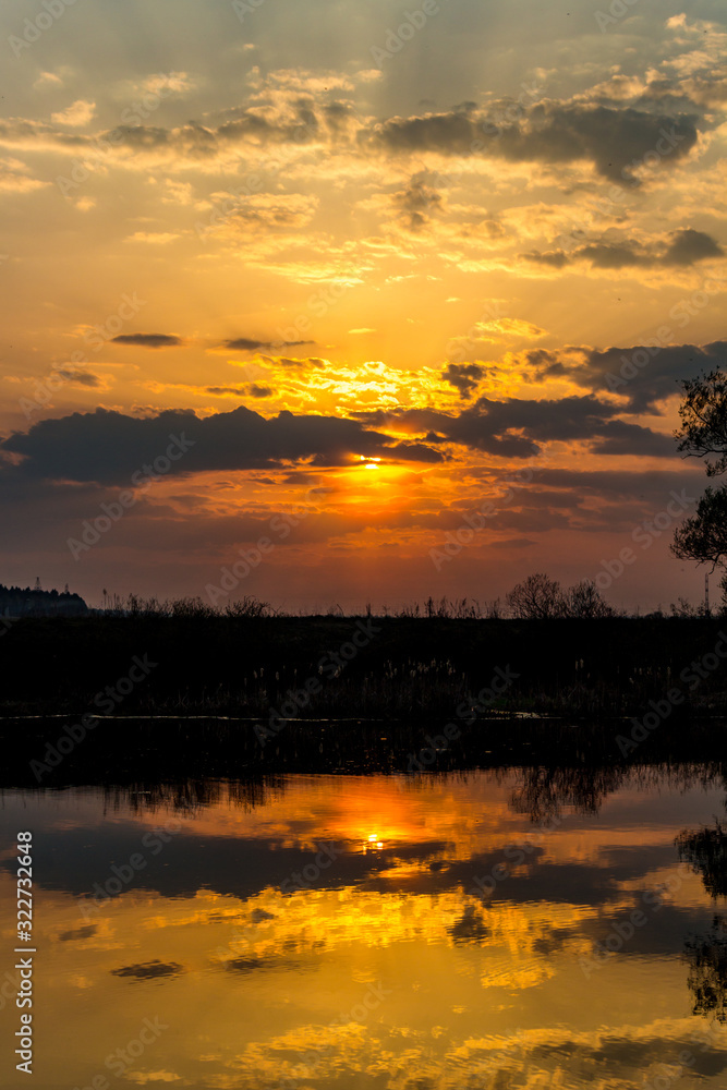 Colorful sunset behind the clouds above the water, vertical view Colorful sunset behind the clouds above the water, vertical view