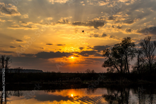 Colorful sunset behind the clouds and ripples of water on the river