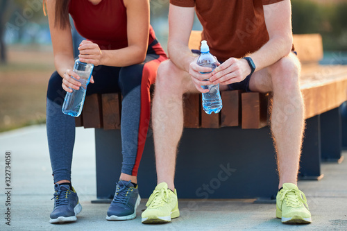 Modern couple making pause in an urban park during jogging / exercise.