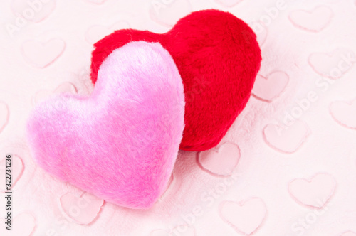 Pair of fluffy pink and red plush hearts sitting on a Valentine's Day background