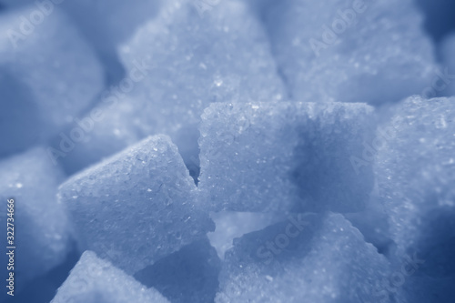Background from pieces of refined sugar tinted in the classic blue color. Macro mode. Selective focus.Sweet food ingredient, white cube pieces. Concept of cooking, baking, diabetes, calorie content.