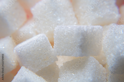 Background of refined sugar pieces. Macro mode. Selective focus.Sweet food ingredient, white pieces of cubes. Concept of cooking, baking, diet, health risk, diabetes, calorie content.