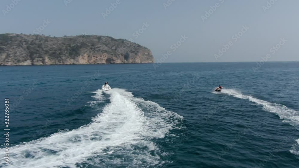 Aerial view of small motorboat pulling people in inflatable water tube Aerial view of small motorboat pulling people in inflatable water tube