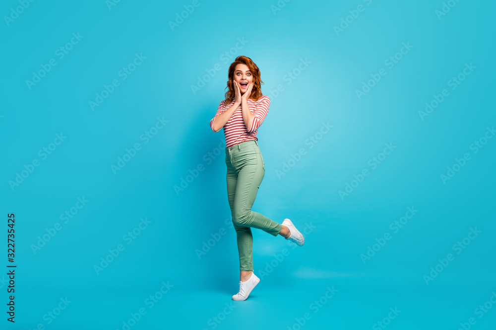 Wow. Full size profile photo of pretty lady enjoy traveling abroad watch amazing view sightseeing wear casual red white shirt green pants footwear isolated blue color background Wow. Full size profile photo of pretty lady enjoy traveling abroad watch amazing view sightseeing wear casual red white shirt green pants footwear isolated blue color background