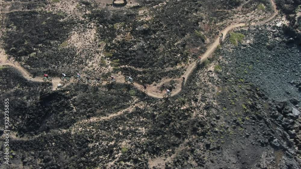 Aerial shot of a group of cyclists riding through vast rock landscape Aerial shot of a group of cyclists riding through vast rock landscape