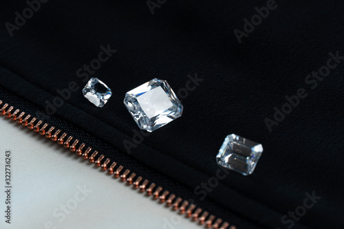 diamond or gemstone in emerald cut on black fabric with gold zipper fashion background