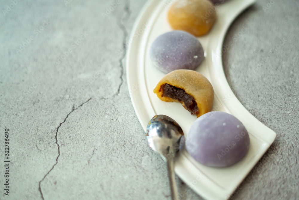 Multi-colored Japanese Mochi in rice dough and on a beautiful plate and concrete background. Traditional Japanese dessert. Multi-colored Japanese Mochi in rice dough and on a beautiful plate and concrete background. Traditional Japanese dessert.
