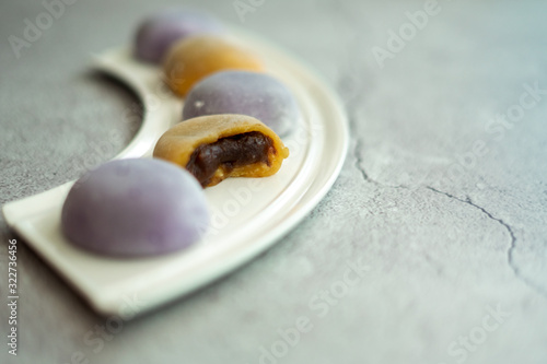 Multi-colored Japanese Mochi in rice dough and on a beautiful plate and concrete background. Traditional Japanese dessert.
