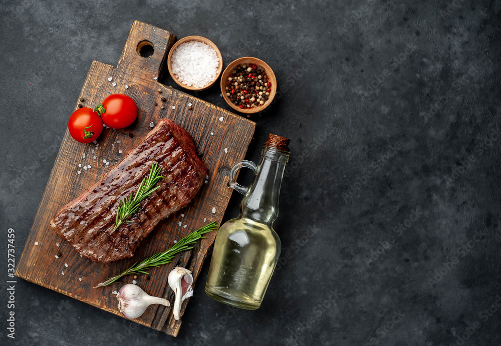 grilled beef steak on a wooden board with spices on a stone background with copy space for your text grilled beef steak on a wooden board with spices on a stone background with copy space for your text