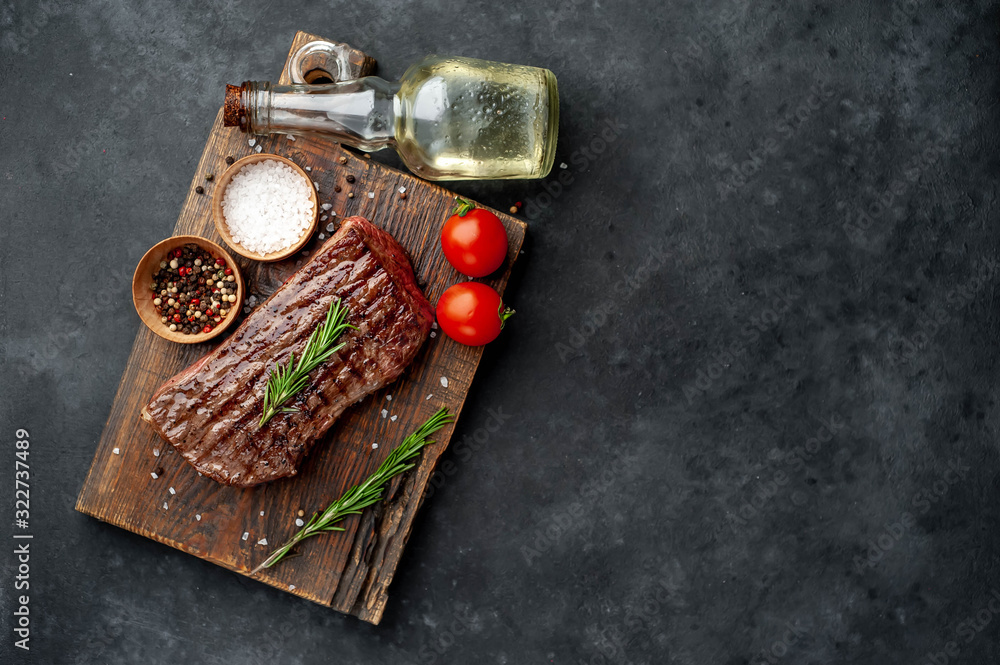 grilled beef steak on a wooden board with spices on a stone background with copy space for your text grilled beef steak on a wooden board with spices on a stone background with copy space for your text