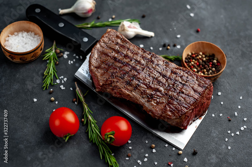 grilled steak over meat knife with spices on a stone background
